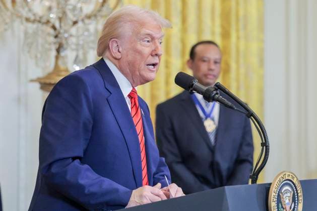 US President Donald J. Trump delivers remarks while standing with golfer Tiger Woods during a reception honoring Black History Month in the East Room of the White House in Washington, DC, on February 20, 2025.  WAX20250220851 SHAWNxTHEW