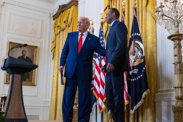 US President Donald J. Trump, with US professional golfer Tiger Woods, walks on stage to deliver remarks during a reception honoring Black History Month in the East Room of the White House in Washington, DC, on February 20, 2025.  WAX20250220861 SHAWNxTHEW