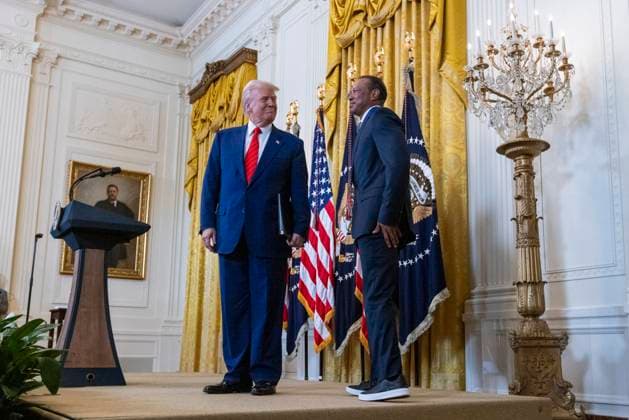 US President Donald J. Trump, with US professional golfer Tiger Woods, walks on stage to deliver remarks during a reception honoring Black History Month in the East Room of the White House in Washington, DC, on February 20, 2025.  WAX20250220867 SHAWNxTHEW