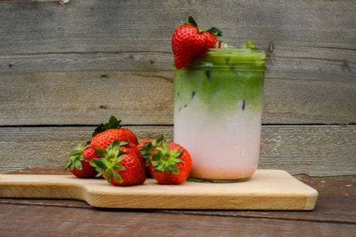 A refreshing strawberry matcha latte in a glass jar with fresh strawberries on a wooden board against a rustic wooden background. 28553227 RECORD DATE NOT STATED