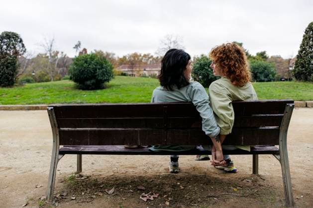 IMAGO Creative, Diversity, Familie: Lesbische Paare Creative Highlights Symbolfotos Smiling lesbian couple holding hands and sitting on park bench model released, Symbolfoto property released, ASGF06181