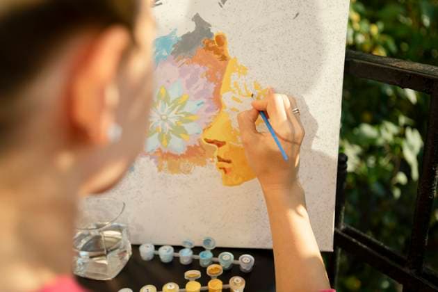 Creative Highlights Symbolfotos A woman paints a paint-by-numbers picture on a balcony during the day model released, Symbolfoto property released, EHAF00452