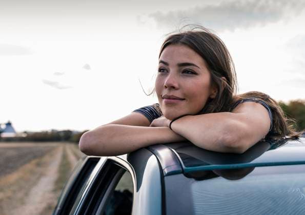 Creative Highlights Symbolfotos Woman leaning on car roof outdoors looking content and happy model released, Symbolfoto, UUF34075