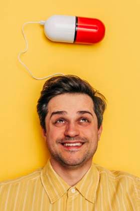 Creative Highlights Symbolfotos Smiling man with a pill above his head on a yellow background model released, Symbolfoto, VSNF02933