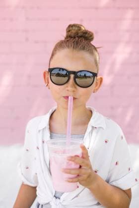 Creative Highlights Symbolfotos Young girl in summery print and sunglasses sips icy pink drink Canada, British Columbia, Fernie R_PKZL250225-1662385-01 ,model released, Symbolfoto