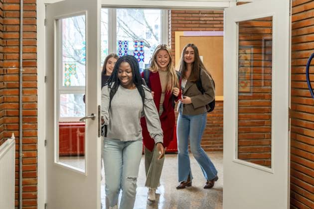 Fröhliche Studentinnen verlassen nach dem Unterricht an der Universität das Klassenzimmer Cheerful female students are walking out of the classroom after their lesson at the university Copyright: imageBROKER UnaixHuizi ibxuhu12778536.jpg ,model released, Symbolfoto ,property released