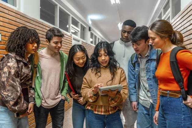 Unterschiedliche Gruppen von Studenten arbeiten gemeinsam an einem Projekt und verwenden dabei ein digitales Tablet in einem Universitätsflur Diverse group of college students collaborating on a project, using a digital tablet in a university hallway Copyright: imageBROKER UnaixHuizi ibxuhu12778545.jpg ,model released, Symbolfoto ,property released