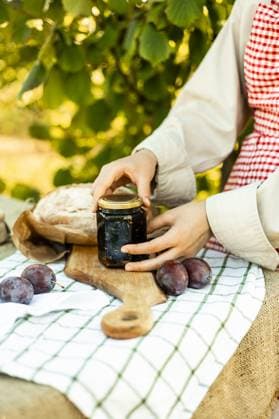IMAGO Creative, Jahreszeit Sommer, Food, Pflaume IMAGO Creative, Jahreszeit Sommer, Food, Marmelade kochen Hands preparing canapes outdoors on a wooden board. Fresh plums, homemade jam, and artisan bread on a rustic tablecloth create a cozy and delicious scene. Model Released Ptashkimenko_ID26208_756091_003 Copyright: xPtashkimenkox