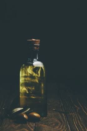A bottle of olive oil with fresh olives on a rustic wooden surface, captured in low light for a moody effect 29267301 RECORD DATE NOT STATED