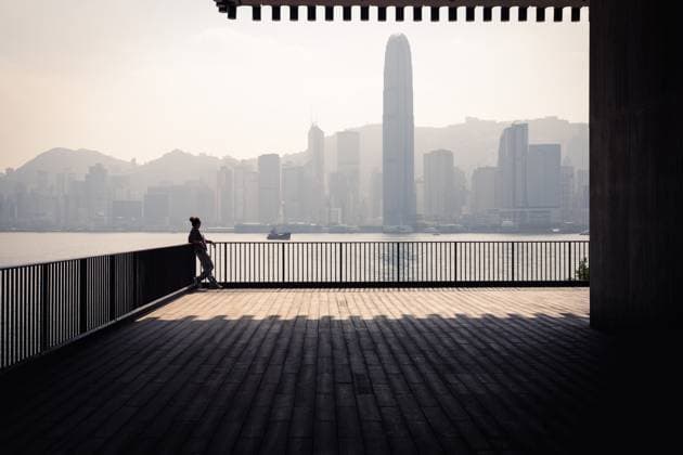 Creative Highlights Symbolfotos Man with hair bun, leaning on railing, looking at Hong Kong Skyline Hong Kong, Hong Kong R_ILLQ250115-1628194-01 ,model released, Symbolfoto