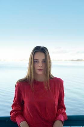 Creative Highlights Symbolfotos Woman in a red shirt stands in front of a serene lake with a calm sky. Miami, FL, USA Miami Florida USA bola07659 Copyright: xConnectxImagesx ,model released