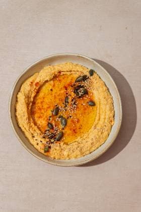 Delicious hummus drizzled with olive oil and garnished with pumpkin seeds and sesame seeds. Served on a rustic ceramic plate, perfect for a Mediterranean-inspired meal. Model Released CintiaViudez_ID27341_784477_007 Copyright: xCintiaxViudezx RECORD DATE NOT STATED