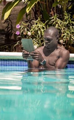 IMAGO Creative, Jahreszeit Sommer, Hitze Black man working on a tablet while relaxing in a tropical pool Las Terrenas, Samaná Province, Dominican Republic R_JURA250318-1685417-01 ,model released, Symbolfoto