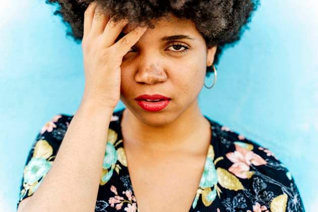 Creative Highlights Symbolfotos Portrait of Afro-American woman, hand on forehead, blue wall in the background model released, Symbolfoto, ERRF01768
