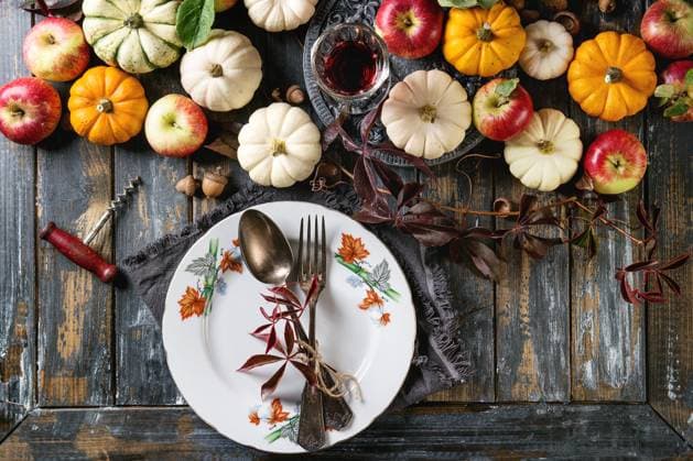 Feiertags-Tischdekoration Autumn holiday table decoration setting with decorative pumpkins, apples, red leaves, empty plate with vintage cutlery, red wine, candle over wooden table. Rustic style. Flat lay Copyright: xZoonar.com NatashaxBreenx 23065050
