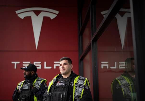 March 29, 2025, Vancouver, B.C, CANADA: Members of the Vancouver Police Department watch as people protest outside the Tesla dealership in Vancouver, B.C., on Saturday, March 29, 2025. Vancouver CANADA  - ZUMAc35_ 20250329_zaf_c35_070 Copyright: xTijanaxMartinx