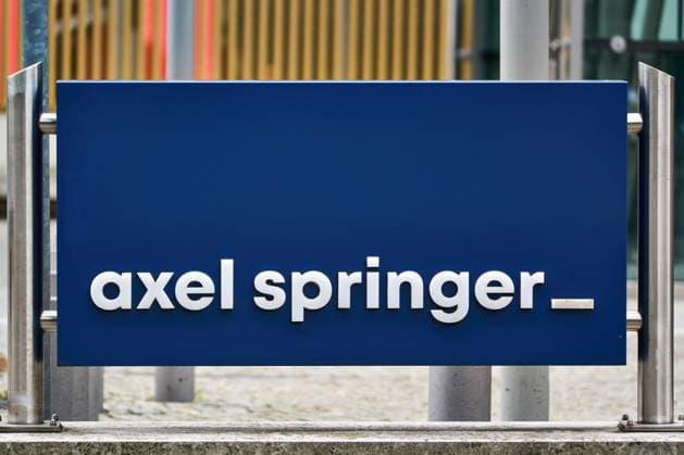 Berlin, Germany - March 27, 2025: Blue sign with white axel springer lettering in front of the Axel Springer skyscraper in Berlin