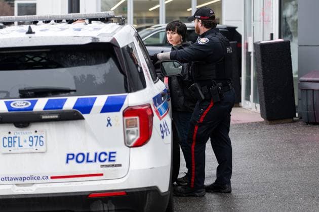 March 31, 2025, Ottawa, On, Canada: A protestor is detained by officers from the Ottawa Police Service (OPS) after the Tesla Service and Showroom centre was damaged with pink spray paint in Ottawa, on Monday, March 31, 2025. Ottawa Canada  - ZUMAc35_ 20250331_zaf_c35_010 Copyright: xSpencerxColbyx