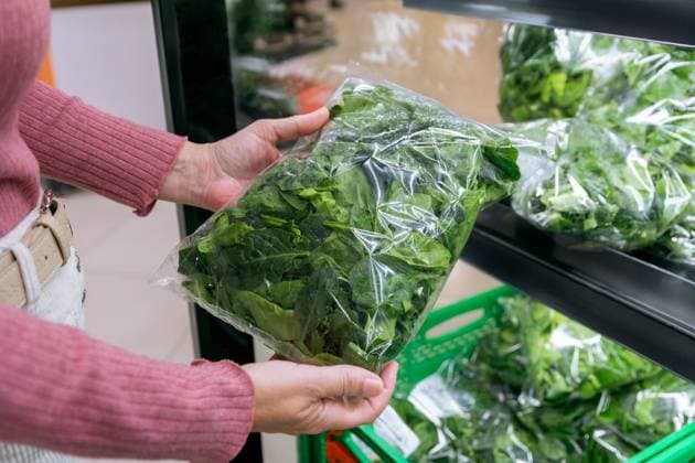 MR_ID27642_20377_RuthAlejo.jpg A woman is holding a bag of fresh spinach in a grocery store. The produce is neatly packaged and displayed on a shelf, showcasing freshness and convenience. Model Released GemaAlejo_ID27642_793910_028 Copyright: xGemaxAlejox
