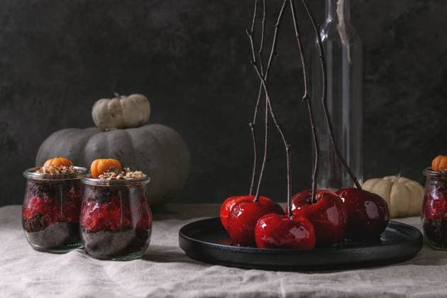 Schokoladen-Halloween-Dessert Layered Halloween dessert chocolate biscuit, raspberry jelly, nuts, marzipan pumpkin in glass jars and red caramel apples on branches served on linen table cloth with decorative pumpkins. Dark mood. Copyright: xZoonar.com NatashaxBreenx 23141157