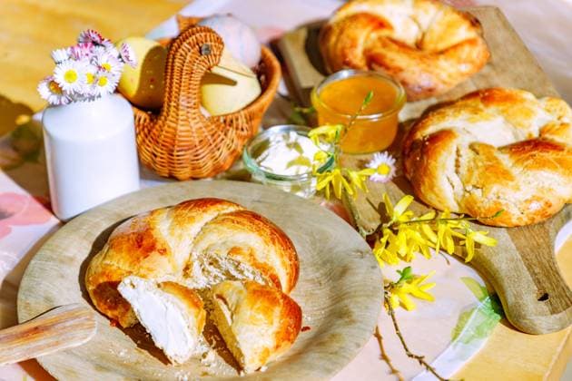 IMAGO Creative, Ostern, Bräuche, Osterbrunch Osterkränzchen auf Holzbrett un Holzteller mit gefärbten Ostereiern in Korbente, Butter und Orangenmarmelade im Glas, Gänseblümchen und Forsythienzweig *** Easter wreath at Wooden board UN Wood plate with colored Easter eggs in Wicker duck, Butter and Orange marmalade at Glass, Daisies and Forsythienzweig