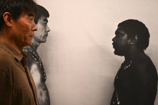 Entertainment Themen der Woche KW15 NATIONAL MUSEUM ABORIGINAL CHINESE EXHIBITION, Zhou Xiaoping, artist, project leader and exhibition curator poses in front of a photograph of himself and Martu artists and fil maker Curtis Taylor during the launch of Our Story: Aboriginal Chinese People in Australia at Focus Gallery in Sydney, New South Wales, Thursday, April 10, 2025. A new exhibition exploring the history of Aboriginal-Chinese Australians opens at the National Museum of Australia, showcasing contemporary artworks, personal accounts, and historical documents. ( NO ARCHIVING, EDITORIAL USE ONLY, NO USE IN BOOKS WITHOUT CONSENT Sydney New South Wales Australia  Copyright: xDeanxLewinsx 20250410162545713135