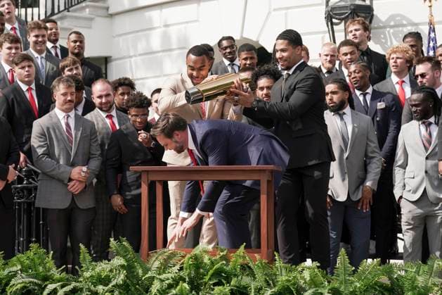 Ohio State University football player TreVeyon Henderson, left, catches the top of the team s championship trophy after Vice President JD Vance tries to pick it up when President Trump welcomed the 2025 College Football National Champions - The Ohio State University on the South Lawn of the White House in Washington, DC on Monday, April 14, 2025.  WAS20250414579 KenxCedeno