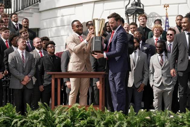 Ohio State University football player TreVeyon Henderson, left, catches the top of the team s championship trophy after Vice President JD Vance tries to pick it up when President Trump welcomed the 2025 College Football National Champions - The Ohio State University on the South Lawn of the White House in Washington, DC on Monday, April 14, 2025.  WAS20250414581 KenxCedeno