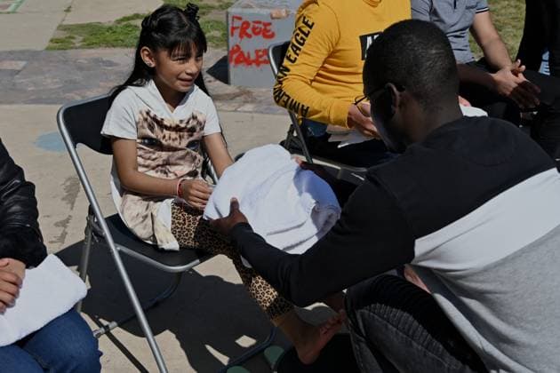 April 17, 2025, Tijuana, Baja California, Mexico: Haitian migrant and volunteer Djephy Wood Denios from La Casa del Migrante in Tijuana, Mexico washes the feet of a young girl during the annual foot washing ceremony where volunteers wash and clean the feet of migrants during a ceremony for holy week in accordance to the twelve apostles remembrance of Jesus Christ Ã¢â‚¬oeFor I have given you an example, that you should do as I have done to youÃ¢â‚¬Â as Father Pat Murphy compares Jesus act to migrants plight and the unfair treatment of migrants and urged for a time of reflection for those seeking the right to freedom of movement and humanitarian asylum on Thursday, April 17, 2025 at TijuanaÃ¢â‚¬â ¢s Friendship Park circle on the US-Mexico bo - ZUMAm180 20250417_zip_m180_018 Copyright: xCarlosxA.xMorenox