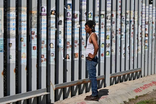 April 17, 2025, Tijuana, Baja California, Mexico: A man looks at photographs of missing persons attached to the Mexico-US border fence in Playas de Tijuana, Mexico as the annual foot washing ceremony was being held nearby as volunteers wash and clean the feet of migrants during a ceremony for holy week. Tijuana Mexico - ZUMAm180 20250417_zip_m180_014 Copyright: xCarlosxA.xMorenox