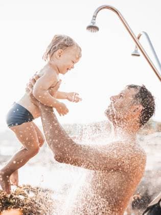 Creative Highlights Symbolfotos Papa und Baby unter einer tropischen Dusche. Papa und sein süßer kleiner Junge spielen am Strand unter der Dusche Wasser spritzt - Vater kümmert sich um süße Sonne in spielerischen Moment im Sommer Familienurlaub. Dad and baby under a tropical shower. dad and his cute infant boy playing on the beach under shower water splashes - Father taking care of cute sun in playful moment at summer family holiday. (License=RF) ,model released, Symbolfoto Copyright: xZoonar.com MatejxKastelicx 23221578 ,model released, Symbolfoto ,property released