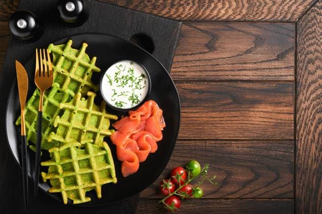 Grüne belgische Waffeln. Spinat-, Bärlauch- oder Pesto-Waffeln mit rotem Lachs und Sahnesauce auf schwarzem Teller vor dunklem, rustikalem Holzhintergrund. Leckeres Frühstück, Snack, Brunch. Ansicht von oben. Attrappe Green Belgian waffles. Spinach or wild garlic or pesto waffles with red salmon and cream sauce on black plate over dark rustic wooden background. Delicious breakfast, snack, brunch. Top view. Mock up (License=RF) Copyright: xZoonar.com KatsiarynaxHuravax 23226429
