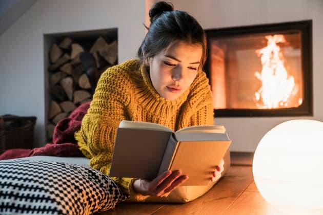 Woman reading a book by the fireplace at home in a cozy setting model released, Symbolfoto property released, UUF34253