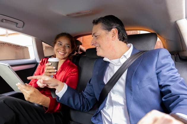 Business colleagues discussing work on a tablet in a car model released, Symbolfoto, ALZF01213