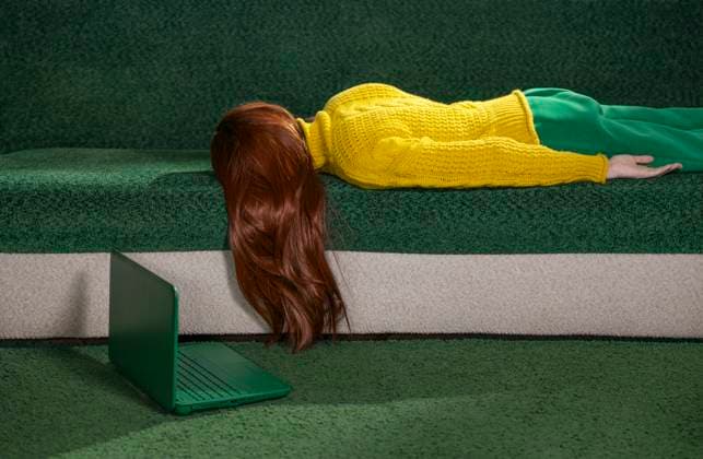 IMAGO Creative, Gesellschaft, Leisure Sickness Red-haired woman lying on a couch at home with a laptop, appearing tired and resting. model released, Symbolfoto, MBLF00807