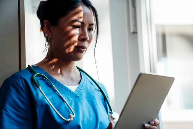 IMAGO Creative, Diversity, Pflege im Krankenhaus Nurse in blue scrubs using a tablet indoors during a break model released, Symbolfoto property released, RAYF00177