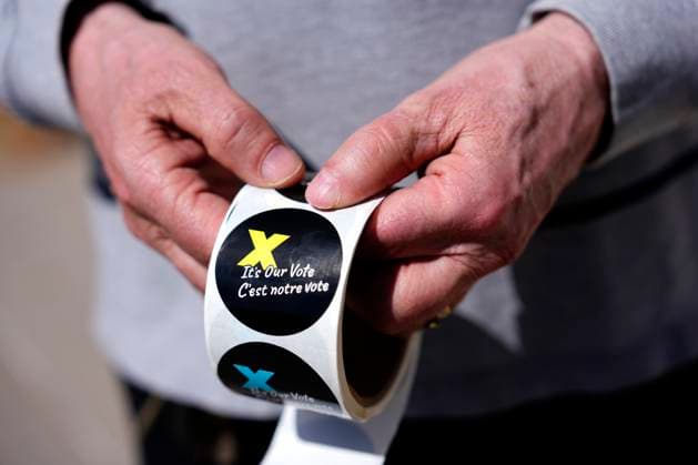 April 28, 2025, Ottawa, On, CAN: A voting information officer holds stickers to be given to voters after casting their ballots, outside a polling location in Ottawa on Monday, April 28, 2025. Ottawa CAN  - ZUMAc35_ 20250428_zaf_c35_007 Copyright: xJustinxTangx