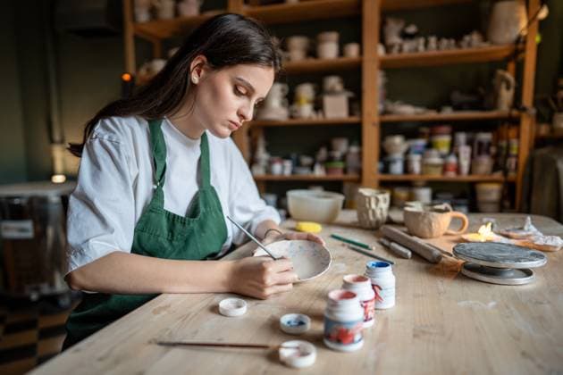 Konzentrierte Keramikerin, die in einer Töpferschule Geschirr aus Ton mit Farben dekoriert. Kleines Geschäft Concentrated craftswoman decorates clay tableware with paints in ceramic studio. Female artisan, small business, pottery art, unique design, handcrafted crockery, manual labor in pottery school (License=RF) ,model released, Symbolfoto Copyright: xZoonar.com DmitriixMarchenkox 23266975 ,model released, Symbolfoto ,property released
