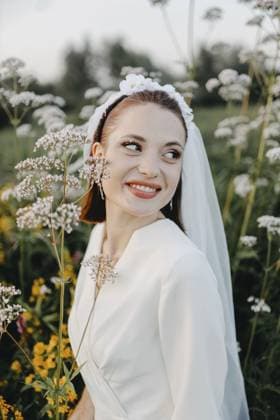 Braut in einem Blumenfeld, strahlend lächelnd, einen fröhlichen und natürlichen Moment einfangend Bride in a field with flowers, smiling brightly, capturing a joyful and natural moment Copyright: imageBROKER MikalaixSayevich ibxwsp12689567.jpg ,model released, Symbolfoto ,property released