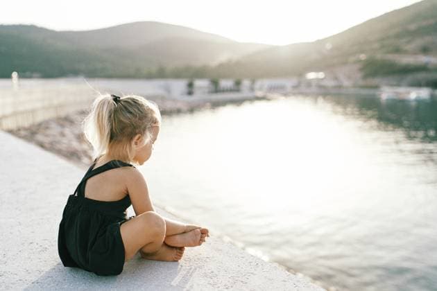 Creative Highlight Symbolbilder Kleines barfüßiges Mädchen sitzt im Schneidersitz auf dem Steg und schaut auf das Wasser. Seitenansicht Little barefoot girl sits cross-legged on the pier and looks at the water. Side view. Copyright: imageBROKER NadtochiyxVladimir ibxiqx13181460.jpg ,model released, Symbolfoto ,property released