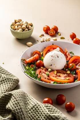 A vibrant salad featuring creamy burrata, juicy tomatoes, and crunchy pistachios. Served in a white bowl with a fresh texture, perfect for a nutritious meal experience. Model Released StudioMostaza_ID28208_830854_004 Copyright: xStudioxMostazax RECORD DATE NOT STATED