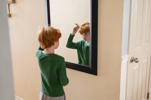 Creative Highlight Symbolbilder Young boy combs hair focused in mirror during morning routine Grimes, Iowa, United States CR_LIPF250507-1722324-01 ,model released, Symbolfoto