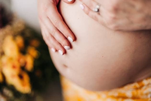 IMAGO Creative, Diversity, Mütter Close-up of hands gently cradling a bare pregnant belly North Andover, Massachusetts, United States R_FKNH250507A-1659374-01 ,model released, Symbolfoto