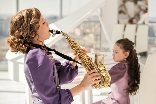 Young Girl Playing Saxophone with Friend in Background Saint Petersburg, Saint Petersburg, Russia R_YFCG250515-1729341-01 ,model released, Symbolfoto