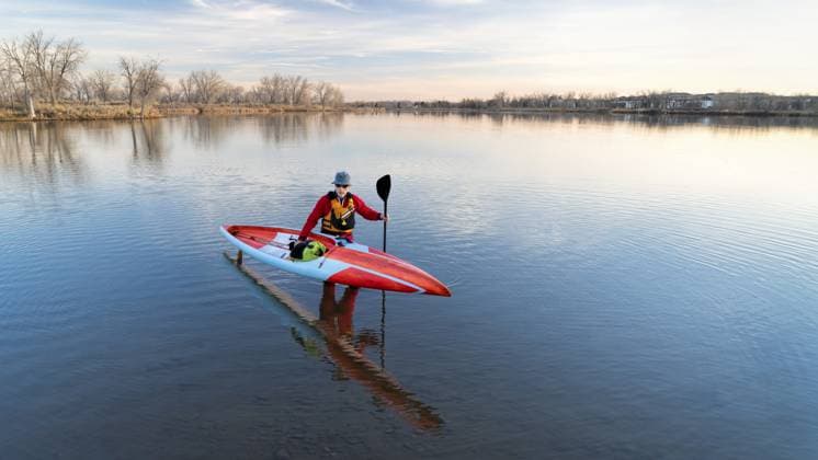 Älterer männlicher Paddler in einem Trockenanzug und Schwimmweste beendet sein Training mit einem langen Renn Stand Up Paddleboard auf einem See in Colorado, Winter oder frühen Frühling Landschaft, Erholung, Fitness und Training Konzept Senior male paddler in a drysuit and life jacket is finishing his workout with a long racing stand up paddleboard on a lake in Colorado, winter or early spring scenery, recreation, fitness and training concept Copyright: imageBROKER MarekxUliasz ibxiqx13544378.jpg ,model released, Symbolfoto ,property released