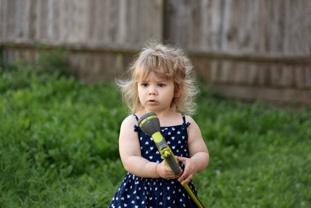 Creative Highlights Symbolbilder Toddler girl holds water hose to spray grass at backyard garden Corby, England, United Kingdom R_JNDO250519B-1727592-01 ,model released, Symbolfoto