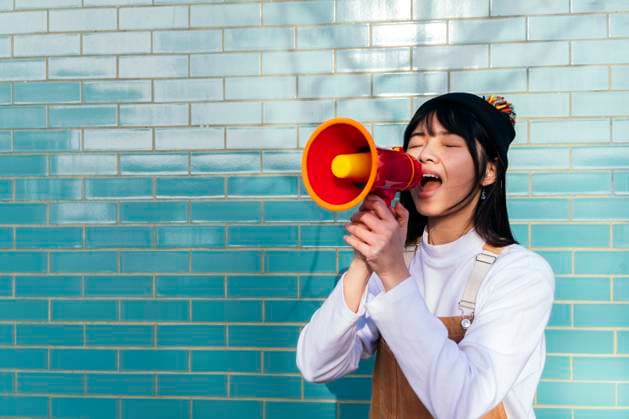 Creative Highlights Symbolbilder Young woman shouting through megaphone in front of turquoise brick wall model released, Symbolfoto, ASGF01990