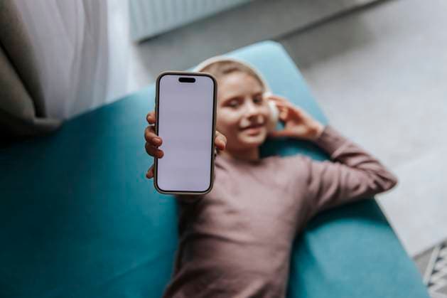 Girl showing a smartphone with a blank screen while relaxing indoors model released, Symbolfoto property released, HDF00199