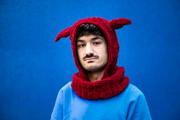 Creative Highlights Symbolbilder Young man in urban clothing with a red knit hat against a blue background model released, Symbolfoto, LMCF02384