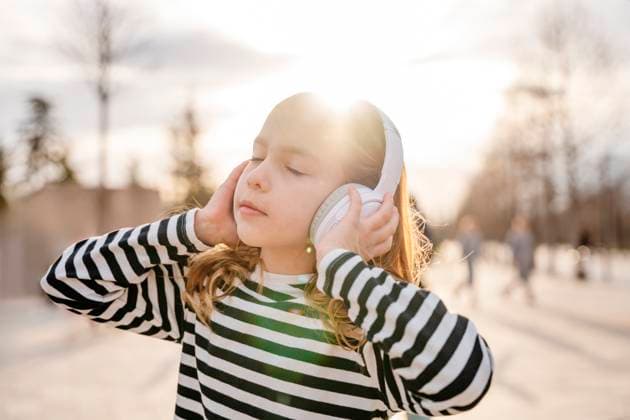 Creative Highlights Symbolbilder Girl enjoying music with headphones in a sunny park model released, Symbolfoto, NLAF00651